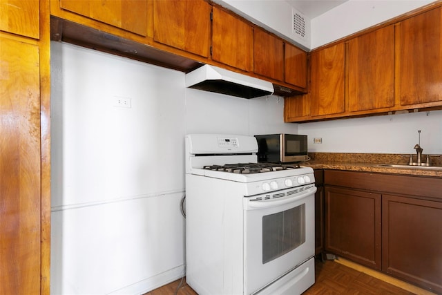 kitchen featuring white gas stove, dark parquet floors, and sink