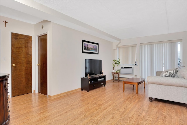 living room with a wall mounted air conditioner, baseboard heating, and light hardwood / wood-style flooring