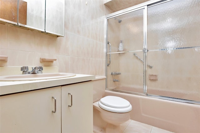 full bathroom with tile patterned flooring, combined bath / shower with glass door, toilet, vanity, and tile walls