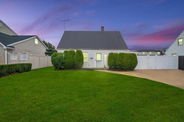 back house at dusk featuring a yard