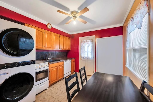 kitchen with sink, plenty of natural light, stacked washer / drying machine, white appliances, and light tile patterned floors