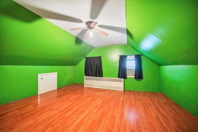 additional living space featuring hardwood / wood-style floors, ceiling fan, radiator, and vaulted ceiling