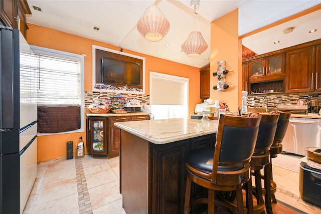 kitchen featuring a kitchen bar, backsplash, stainless steel dishwasher, pendant lighting, and a center island