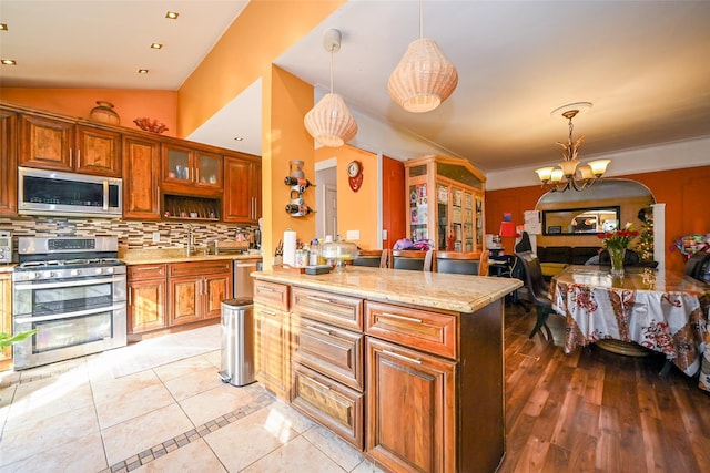 kitchen with tasteful backsplash, an inviting chandelier, decorative light fixtures, and appliances with stainless steel finishes