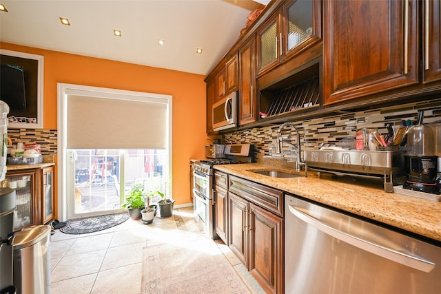 kitchen with light stone countertops, sink, decorative backsplash, light tile patterned floors, and appliances with stainless steel finishes