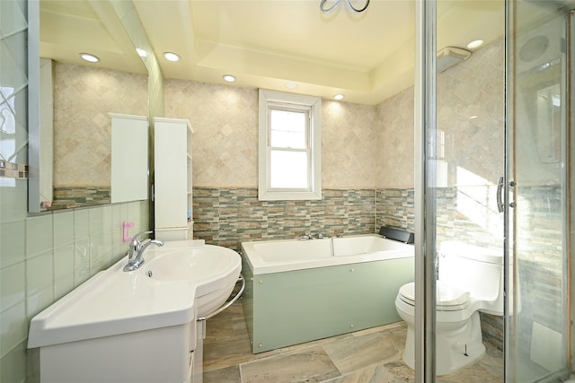 bathroom with vanity, a tub to relax in, toilet, and tile walls