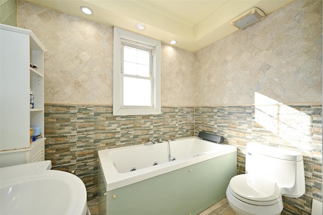 bathroom featuring a bath, toilet, tile walls, and sink