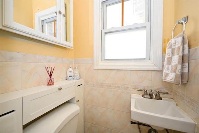 bathroom featuring toilet, tile walls, and sink