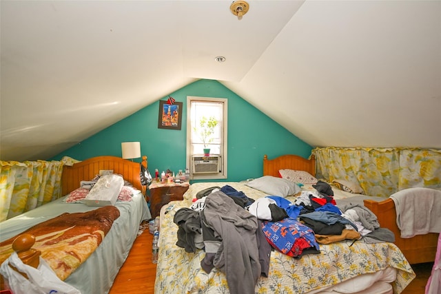 bedroom featuring cooling unit, wood-type flooring, and vaulted ceiling