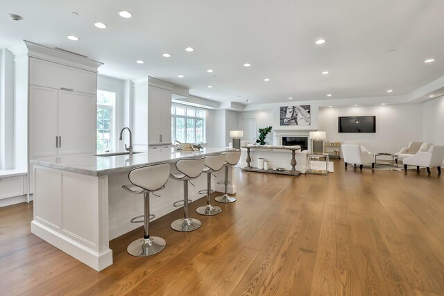 2 Weaver St Unit 3, Scarsdale, NY 10583 - kitchen featuring a kitchen breakfast bar, a spacious island, light stone countertops, light wood-type flooring, and white cabinetry
