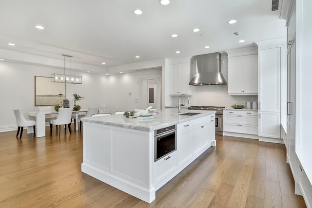 2 Weaver St Unit 3, Scarsdale, NY 10583 - kitchen featuring white cabinetry, sink, wall chimney exhaust hood, an island with sink, and light hardwood / wood-style floors