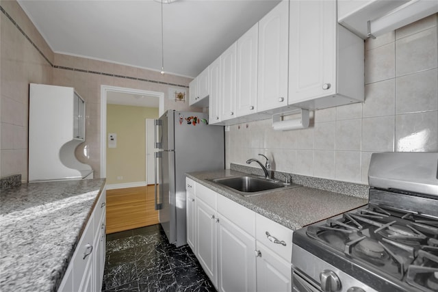 kitchen with sink, stainless steel fridge, tasteful backsplash, white cabinetry, and range with gas cooktop