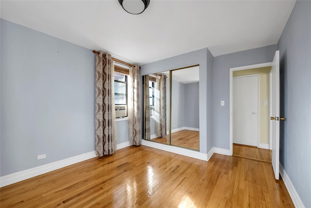 unfurnished bedroom with light wood-type flooring and a closet