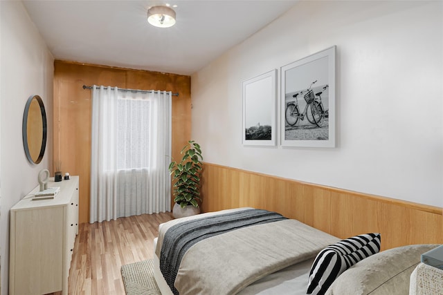 bedroom featuring wooden walls and light wood-type flooring