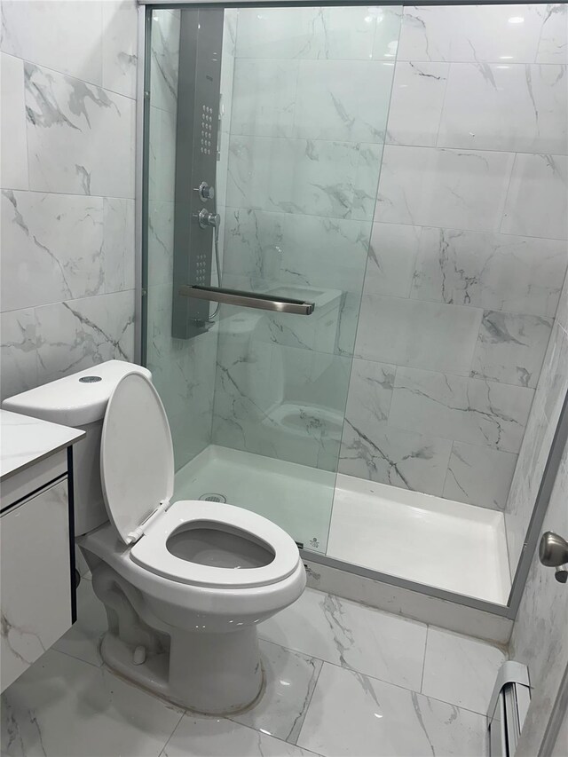 bathroom featuring toilet, a tile shower, tile walls, and vanity