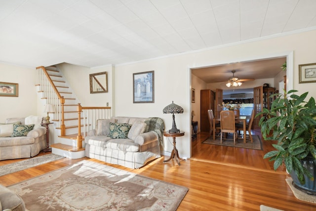 living room with wood-type flooring, ceiling fan, and ornamental molding