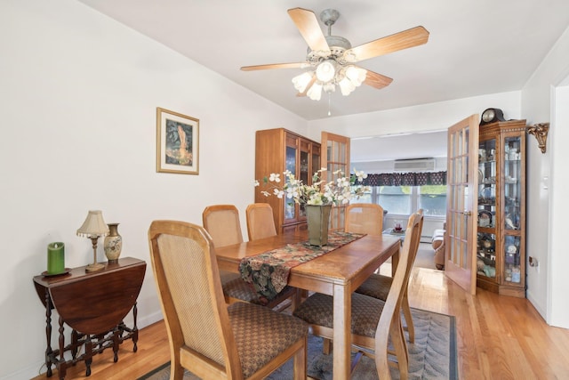 dining room with ceiling fan, an AC wall unit, and light hardwood / wood-style flooring