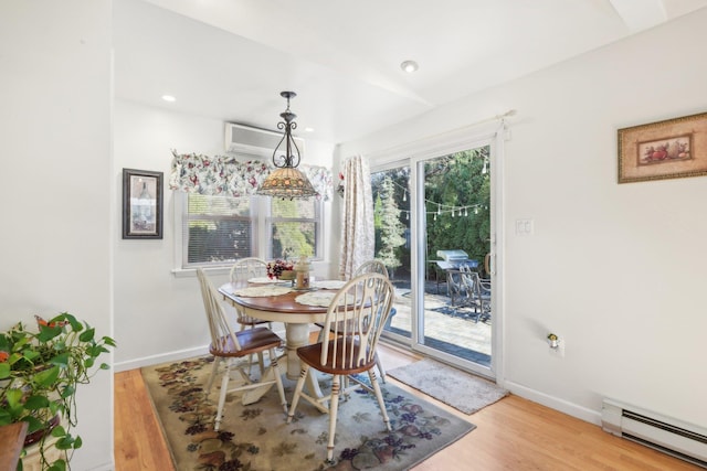 dining space featuring a wall mounted AC, light hardwood / wood-style flooring, and baseboard heating