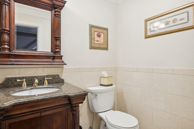 bathroom with vanity, toilet, tile walls, and ornamental molding