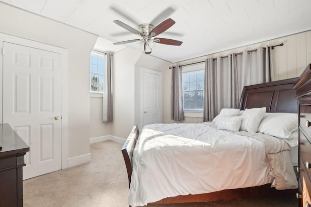 bedroom featuring ceiling fan, light colored carpet, and multiple windows