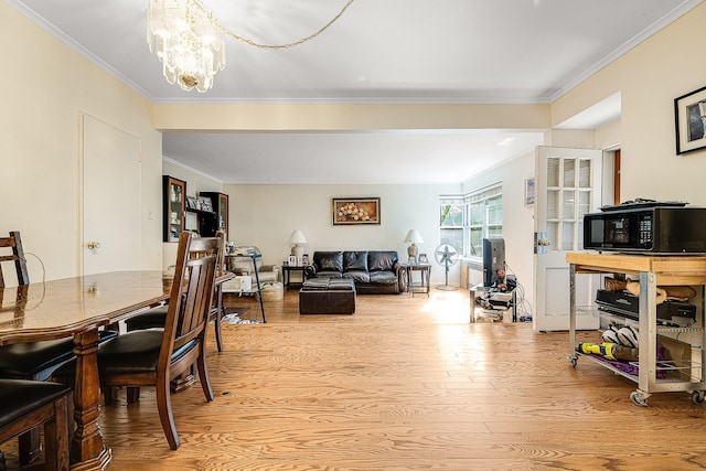 dining room with light hardwood / wood-style floors, ornamental molding, and an inviting chandelier