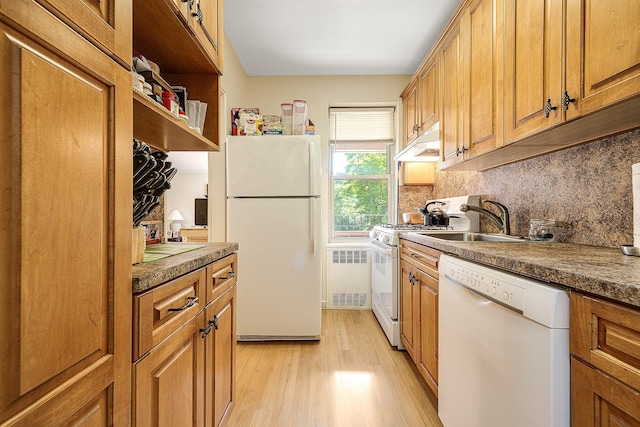 kitchen with light wood-type flooring, tasteful backsplash, white appliances, sink, and radiator heating unit