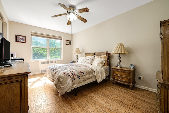 bedroom with radiator heating unit, hardwood / wood-style flooring, and ceiling fan