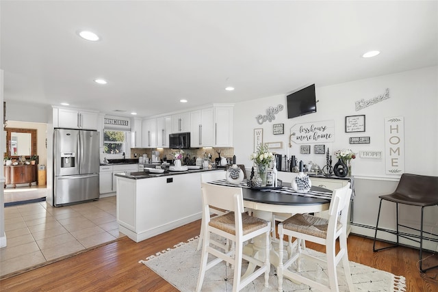 kitchen with hardwood / wood-style flooring, decorative backsplash, stainless steel fridge, and white cabinetry