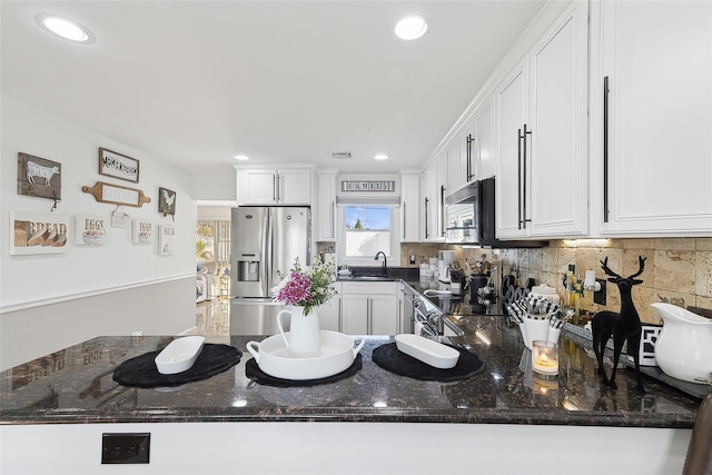 kitchen with dark stone countertops, white cabinetry, kitchen peninsula, and appliances with stainless steel finishes