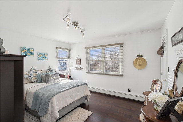 bedroom featuring rail lighting, dark wood-type flooring, and a baseboard heating unit