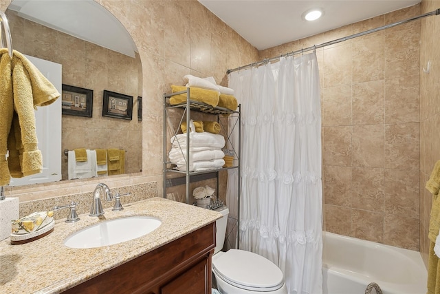 full bathroom featuring vanity, shower / bathtub combination with curtain, tile walls, and toilet