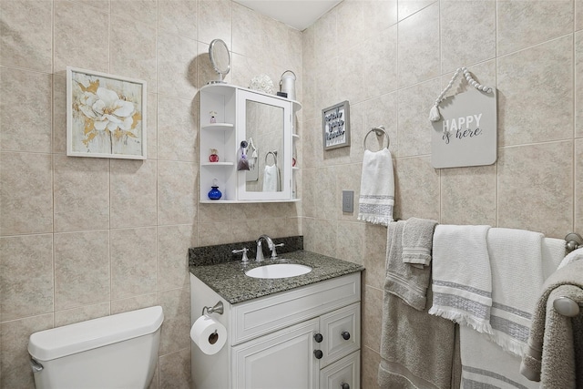 bathroom with vanity, tile walls, and toilet