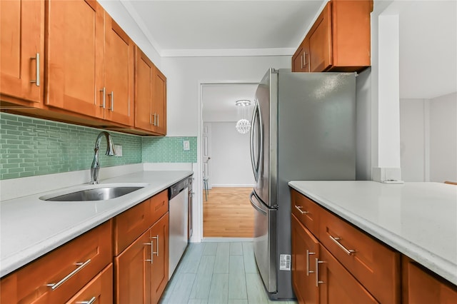 kitchen featuring appliances with stainless steel finishes, sink, backsplash, ornamental molding, and light wood-type flooring