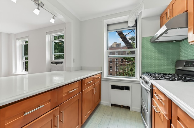 kitchen with tasteful backsplash, cooling unit, track lighting, stainless steel gas stove, and radiator heating unit