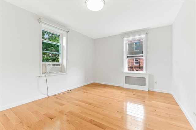 spare room featuring hardwood / wood-style flooring, a wealth of natural light, and cooling unit