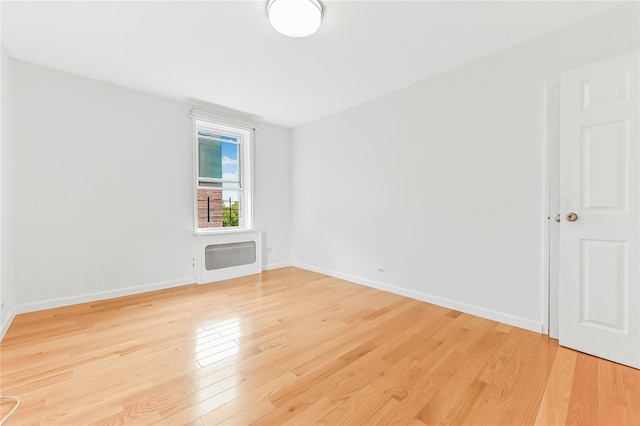 unfurnished room featuring heating unit and hardwood / wood-style floors