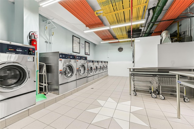 clothes washing area featuring light tile patterned floors and washing machine and dryer