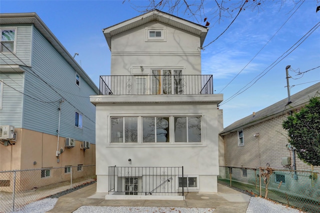 back of property with a wall mounted AC and a balcony