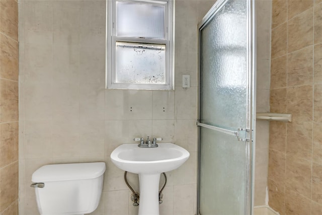 bathroom featuring sink, toilet, an enclosed shower, and tile walls