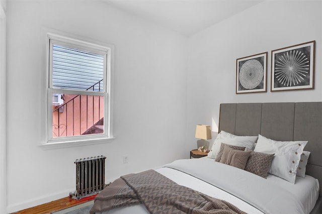 bedroom featuring hardwood / wood-style floors and radiator heating unit