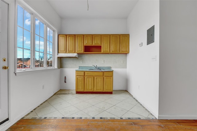 kitchen with light tile patterned floors, sink, electric panel, and tasteful backsplash