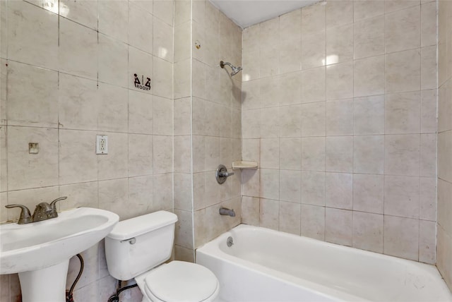 full bathroom featuring sink, tiled shower / bath, tile walls, and toilet