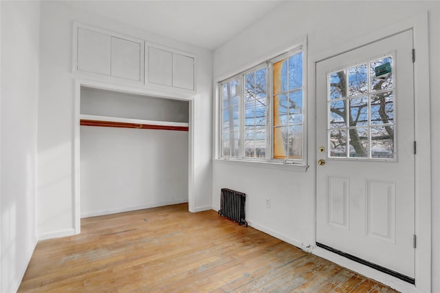 interior space with radiator heating unit, light hardwood / wood-style flooring, and a healthy amount of sunlight