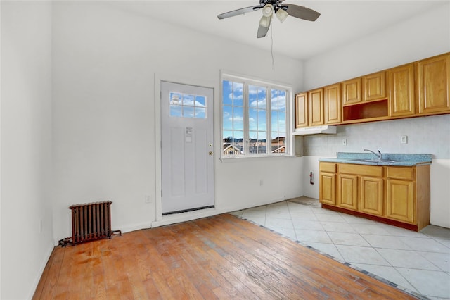 kitchen featuring backsplash, ceiling fan, sink, light hardwood / wood-style flooring, and radiator heating unit