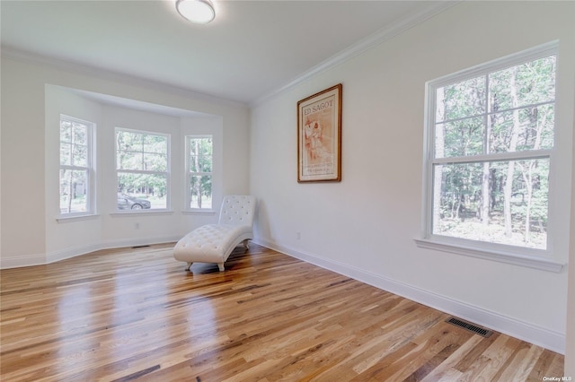 living area with crown molding, a healthy amount of sunlight, and light hardwood / wood-style floors