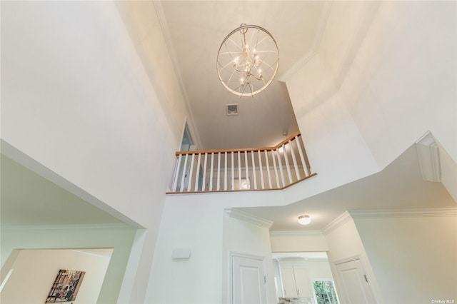 staircase with ornamental molding, a high ceiling, and an inviting chandelier