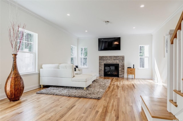 living room with a fireplace, a wealth of natural light, crown molding, and light hardwood / wood-style floors