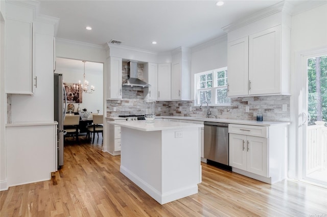 kitchen with appliances with stainless steel finishes, light hardwood / wood-style floors, white cabinetry, and wall chimney exhaust hood