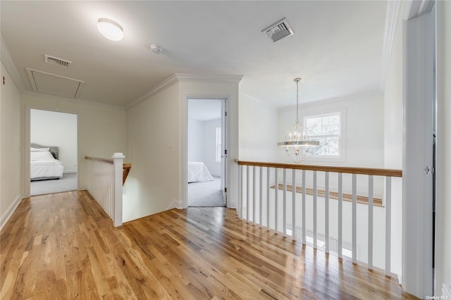 hallway featuring crown molding, light hardwood / wood-style flooring, and a notable chandelier