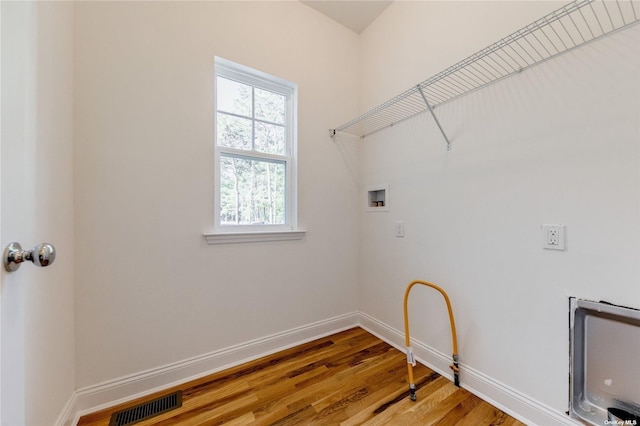 laundry area with heating unit, hookup for a washing machine, and hardwood / wood-style flooring